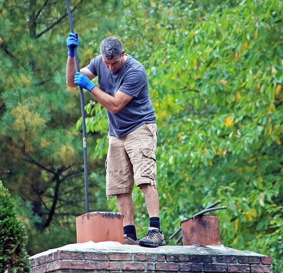 Professional conducting chimney sweeping services, maintaining and cleaning a residential chimney for safety.