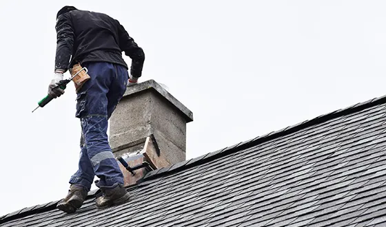 Worker doing chimney flue maintenance on a roof to keep it safe and working well